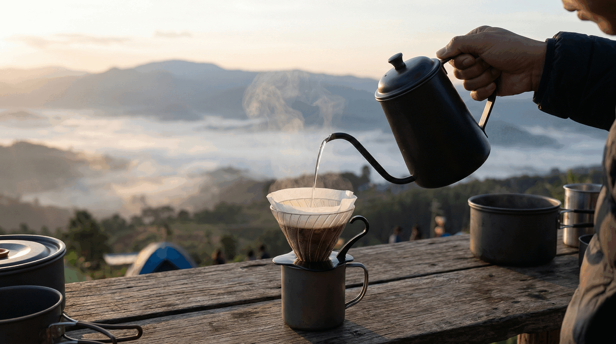 A gooseneck kettle pouring hot water into a coffee dripper at a mountain camp in Mae Hong Son.