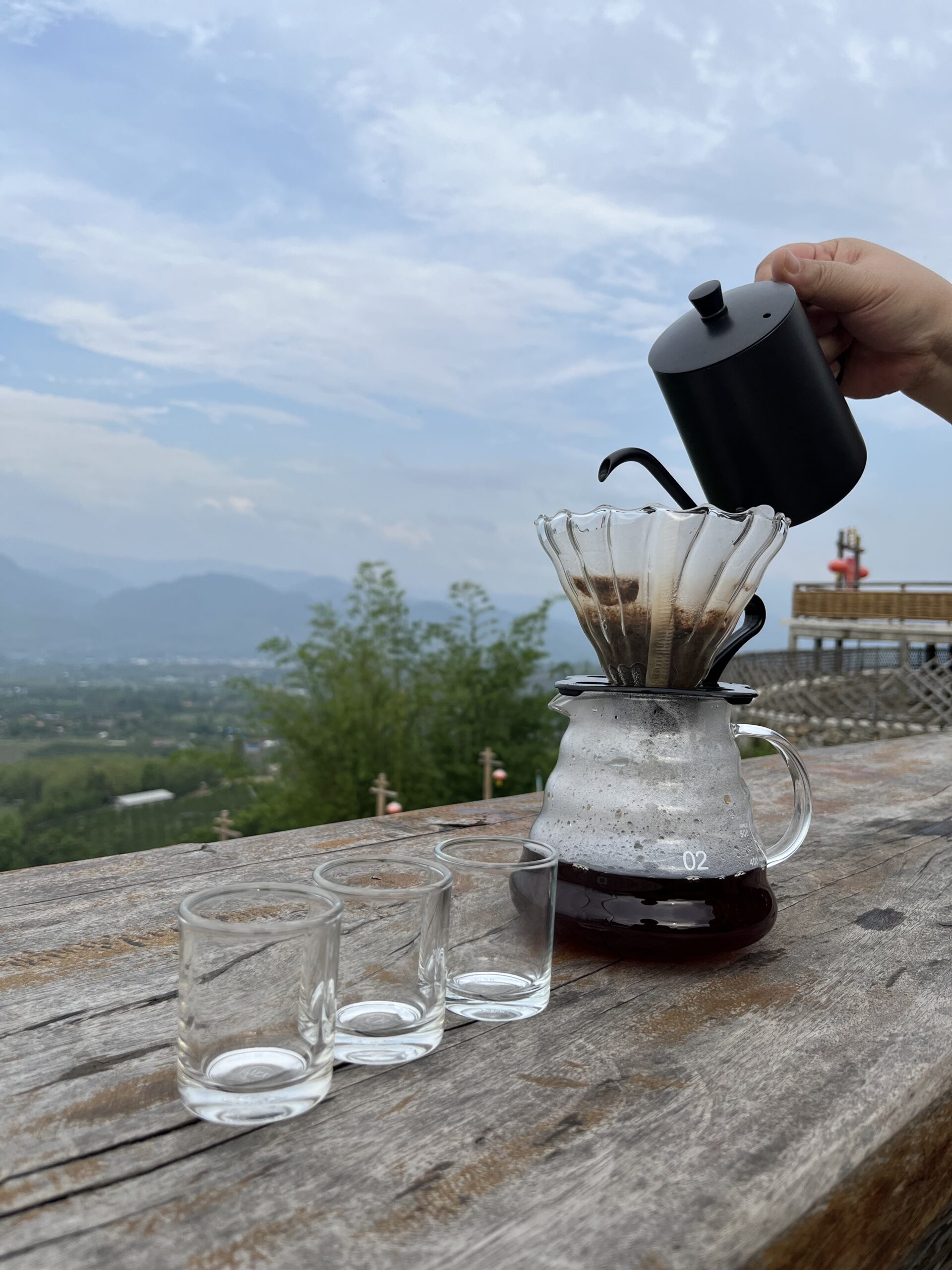 Brewing specialty coffee outdoors with portable gear at a foggy campsite in Huai Nam Dang, Mae Hong Son